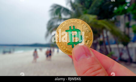 Mano azienda golden bitcoin sulla spiaggia, sullo sfondo delle onde del mare. Bitcoin è un moderno modo di scambiare questo crypto moneta è un comodo significa Foto Stock