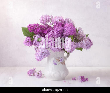 Bouquet lilla in faience brocca su un bianco tavolo di legno. Soft focus. Foto Stock