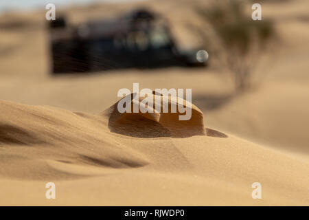 Vento rendendo dune sabbiose vagare con sfocate veicolo fuoristrada nel Sahara occidentale durante una off road trip in Tunisia Foto Stock