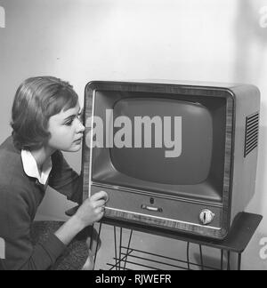 La televisione negli anni cinquanta. Una giovane donna è raffigurato accanto a un tipico 50s televisore. Un tv Grundig in piedi su una tipica stringa di metallo disossate tabella tv. Foto Kristoffersson ref CC93-2. La Svezia 1958 Foto Stock