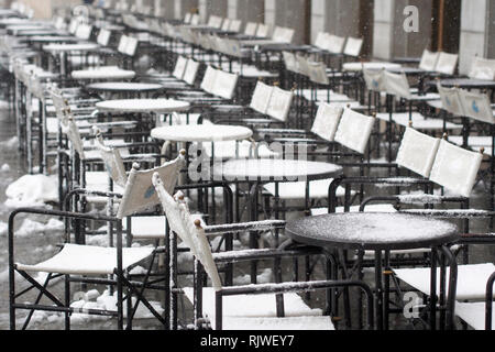 Concetto stagionale dell'immagine. Le sedie e i tavoli di un cafe bar coperte di neve e ghiaccio. Foto Stock