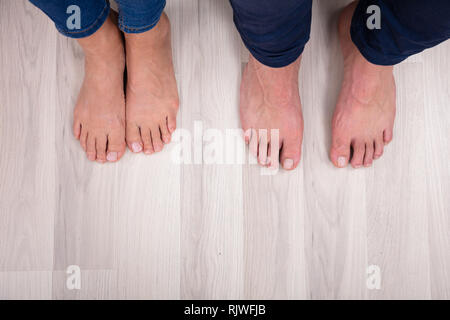 Sezione bassa del giovane con i piedi sul pavimento in soggiorno Foto Stock