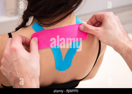 L'uomo applicando speciale Physio Tape sulla donna di Back Foto Stock