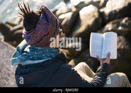 Giovani asiatici barbuto uomo turistica con Libro Divertirsi a Essaouira, Marocco al tramonto di sera tempo. Foto Stock
