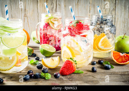 Selezione diversi tipi di frutta e bacche di limonata bevande, ristoro acqua infusa, in vasetti di vetro, con fragole fresche, limone, calce, arance, mirtillo, w Foto Stock