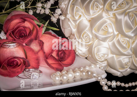 Le rose su piastra bianca con gli anelli di nozze, Perle & Bouquet Foto Stock
