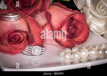 Le rose su piastra bianca con gli anelli di nozze, Perle & Bouquet Foto Stock