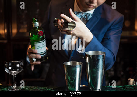 Barman versando gin con un jigger nello shaker di stagno e preparare il cocktail Foto Stock