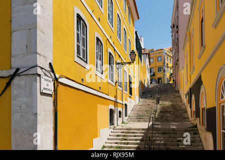Vicolo di scala nella città vecchia di Lisbona con giallo pittoresche facciate di case. Foto Stock
