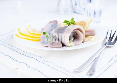 Le aringhe marinate filetto su una piastra bianca con limone e cipolla. Servita la tabella e la molla tradizionale delicatezza dei Paesi Bassi. Cucina tipica f Foto Stock
