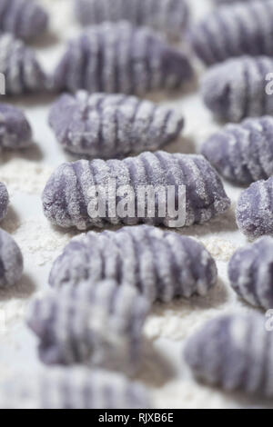 Macro shot di materie gnocchi viola su un bianco porcellana vintage vassoio. Violetta italian gnocchi fatti con patate viola. Foto Stock