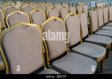 File di disco tradizionali sedie di legno con morbido cuscino e bordatura dorata per incontri formali, conferenze, lezioni, cerimonie di laurea Foto Stock