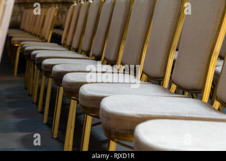 File di disco tradizionali sedie di legno con morbido cuscino e bordatura dorata per incontri formali, conferenze, lezioni, cerimonie di laurea Foto Stock