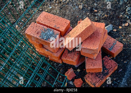 Mattoni rossi sparsi su un cantiere di close-up Foto Stock