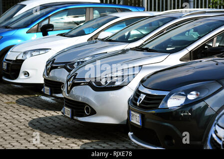 Linea di automobili parcheggiate su un lastricato area di parcheggio in una vista ravvicinata sulla parte anteriore del cofano o del cofano in una linea diagonale Foto Stock