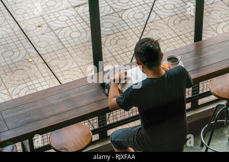 L'uomo la lettura di libri nel coffee shop Foto Stock