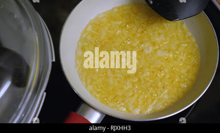 Le cipolle tritate la frittura sul fornello elettrico in olio vegetale su dimensioni medio pan Foto Stock