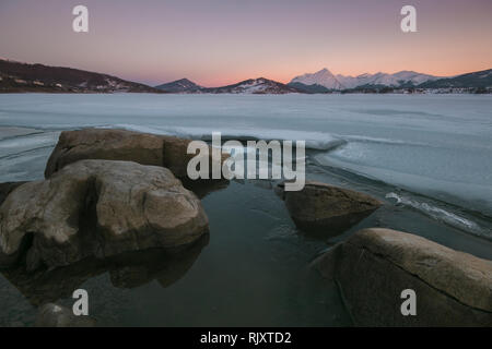 Crepe sulla superficie del ghiaccio. Lago ghiacciato in inverno le montagne. Lago di Campotosto in Gran Sasso e Monti della Laga Parco Nazionale d'Abruzzo Foto Stock