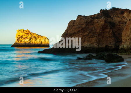 Cielo blu chiaro soleggiato sopra la formazione di roccia in mare, Alvor, Algarve, Portogallo, Europa Foto Stock