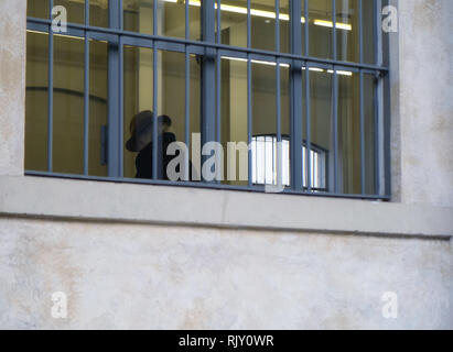 Triste vecchio uomo senior con hat all'interno di edificio con finestre sbarrate - Diritto e Giustizia concetto Foto Stock