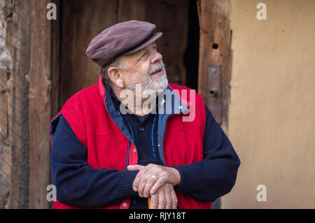 Bel ritratto del barbuto ucraino senior seduta contadina contro il vecchio fienile entrata Foto Stock