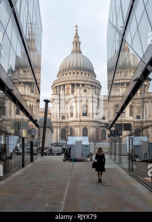 Una solitaria figura cammina verso la Cattedrale di San Paolo. Due riflessi di san Paolo può essere visto in vetro su entrambi i lati. A Londra uno scambio di nuovo. Foto Stock