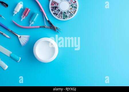 Un set di strumenti di cosmetici professionali per la manicure e la cura delle unghie e per creare bellissimi disegni su uno sfondo blu. Vista dall'alto. Composizione per la scheda con Foto Stock