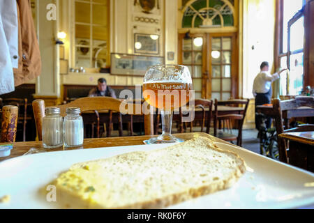 Bruxelles, Belgio - un bicchiere di Gueuze, una speciale birra acida fatta solo a Bruxelles e una fetta di pane al caffè tradizionale a La Morte subite Foto Stock