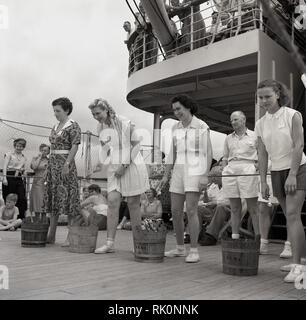 Degli anni Cinquanta, storico, femmina i passeggeri con piccole botti di legno accanto a loro di prendere parte un gioco di coperta a bordo di un battello a vapore Union-Caste. Foto Stock