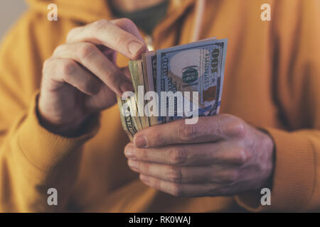 Uomo informale è il conteggio dollaro americano banconote, close up delle mani con il denaro Foto Stock