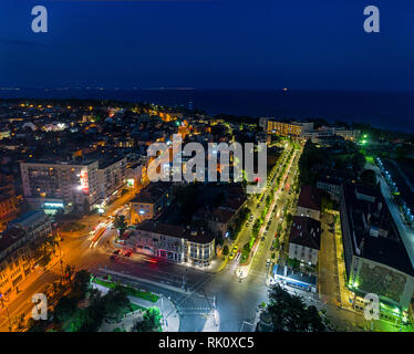 La luce sulla strada rotonda di notte e la città di Burgas, Bulgaria. Strada bellissima vista aerea di incrocio occupato, vista aerea. Foto Stock