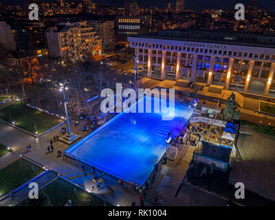 Drone top view.Sono molte le persone di pattinaggio presso la pista in 'Troikata' piazza di sera, vista aerea. Foto Stock