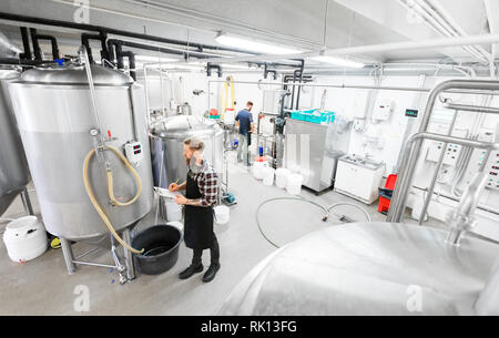 Uomo con appunti alla birreria artigianale o impianto di birra Foto Stock