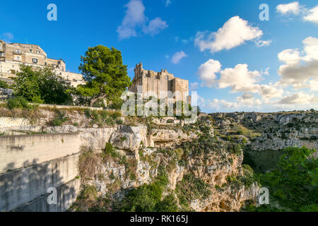 Vista del convento di Sant'Agostino seduto su di una ripida scogliera battuta che si affaccia su un canyon con grotte dei Sassi abitazioni preistoriche in Matera, Italia Foto Stock