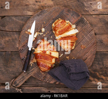 Formaggio e pancetta croissant su un tagliere di legno con il coltello Foto Stock