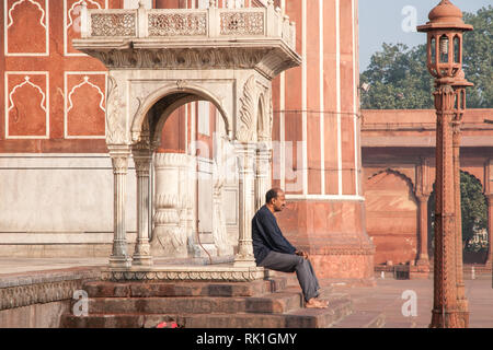 Uomo appoggiato a Jama Masjid moschea nella vecchia Dehli. La moschea fu completata nel 1656 è la più importante di tutte le moschee dall'impero Mughal. Foto Stock