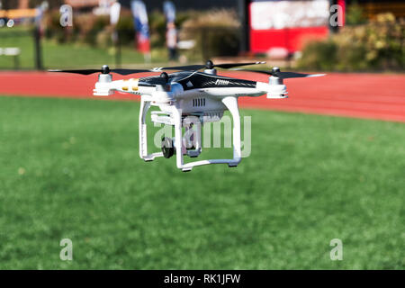 Un drone è tenuto fuori da un tappeto erboso verde campo portare una fotocamera Foto Stock