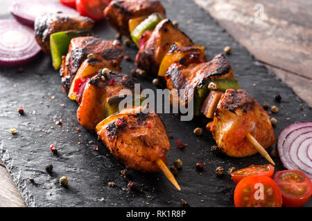 Pollo shish kebab con verdure su pietra nera Foto Stock