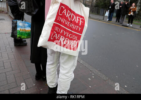 Una persona con un'Università di Cardiff bilingue inglese lingua gallese tela borsa a tracolla in attesa di attraversare la strada in Cardiff Wales UK KATHY DEWITT Foto Stock