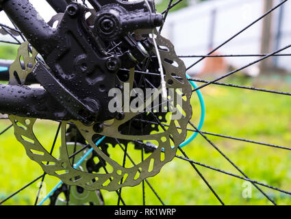 Bagnate dopo la pioggia una bicicletta il disco freno sull'erba verde dello sfondo. Foto Stock