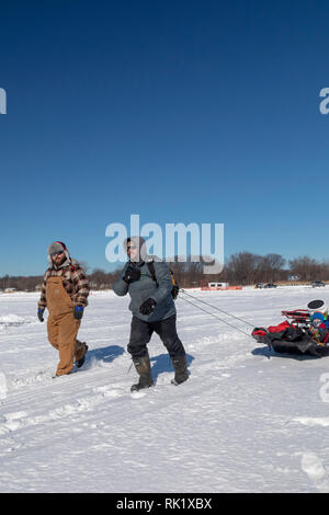 Fair Haven, Michigan - i pescatori di ghiaccio haul i loro attrezzi di pesca e con un bambino piccolo attraverso congelati Anchor Bay sul lago di St. Clair. Foto Stock