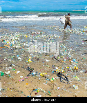 Inquinamento, lone uomo di prelevare le bottiglie di plastica, bicchieri, cannucce e altre lettiere lavato fino sulla spiaggia di Jimbaran, Bali Indonesia.. Foto Stock