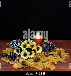 La seta foglie di acero, bel bouquet di girasoli, pigne nelle quali smerigliato e candela arancione sul piano portapaziente con sfondo scuro. Foto Stock