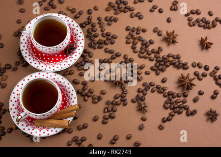 Due piccante di caffè nero polka dot tazze e i chicchi di caffè pasticcio su sfondo marrone Foto Stock