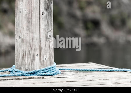 Corda blu avvolto intorno bollard in legno, vicino, ritagliato Foto Stock