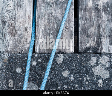 Weathered tavole di legno e calcestruzzo con corda blu, full frame, close up Foto Stock