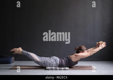 Donna pratica lo yoga, stretching in esercizio Salabhasana, doppia gamba calci pongono Foto Stock