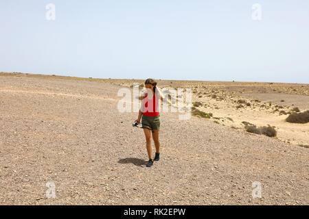 Donna wanderlust attiva avente un viaggio in vacanza ad esplorare l'isola di Lanzarote. Hipster ragazza camminare sul secco superficie arida e godendo di una natura selvatica su Canar Foto Stock