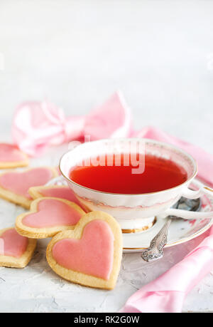 A forma di cuore biscotti frollini e tazza di tè rosso, concetto di San Valentino Foto Stock