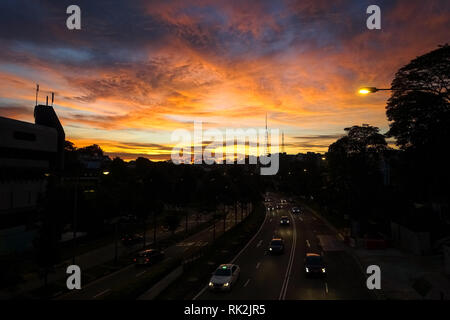 Fari di traffico e Rosa tramonto in nuvole sopra il Bukit Timah Rd. - Città di Singapore Foto Stock